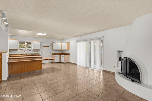 unfurnished living room with light tile patterned flooring, sink, and a textured ceiling