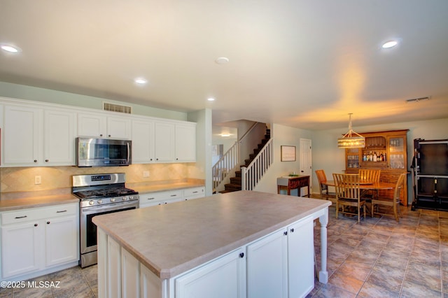 kitchen featuring stainless steel appliances, white cabinetry, and a center island