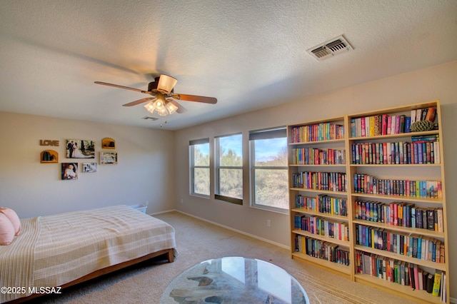 carpeted bedroom featuring ceiling fan and a textured ceiling