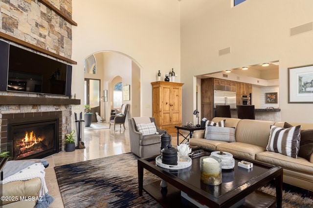 living room with a towering ceiling and a stone fireplace