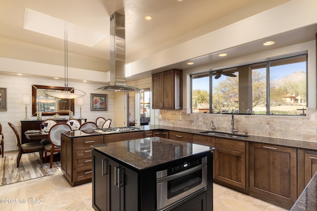 kitchen with sink, a center island, hanging light fixtures, dark stone countertops, and island exhaust hood