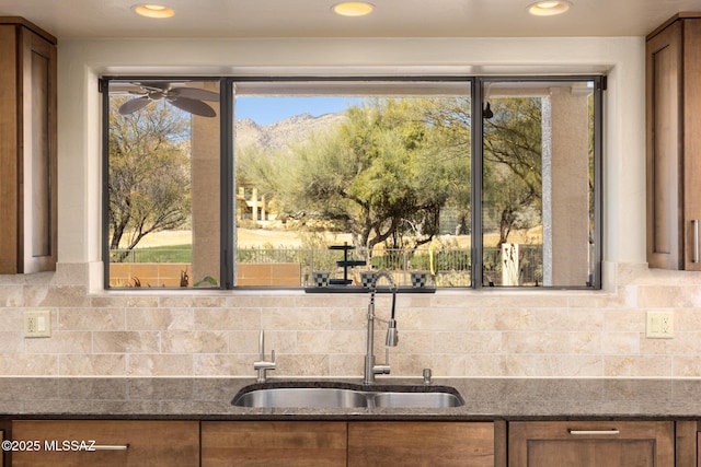 kitchen with dark stone countertops, sink, and ceiling fan