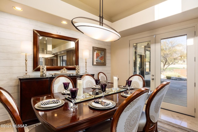 tiled dining space featuring french doors and wood walls