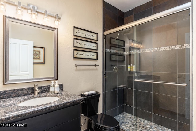 bathroom featuring walk in shower, vanity, and toilet