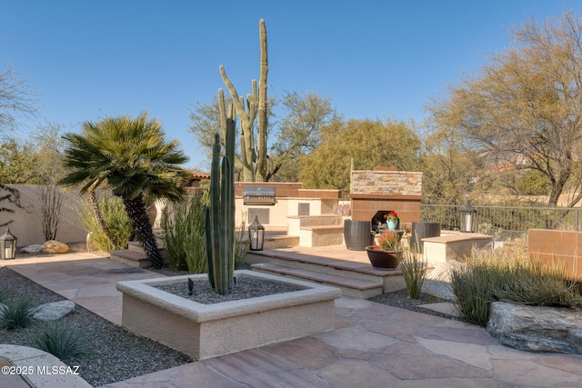 view of patio featuring area for grilling and an outdoor stone fireplace