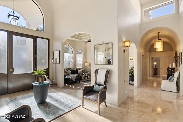 entryway featuring ceiling fan, a towering ceiling, and a healthy amount of sunlight