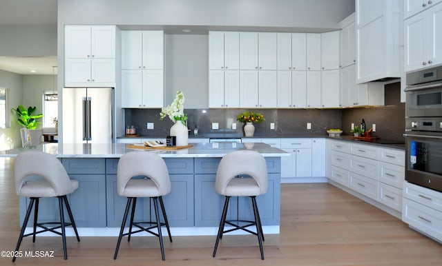 kitchen featuring a kitchen breakfast bar, appliances with stainless steel finishes, tasteful backsplash, white cabinets, and a kitchen island