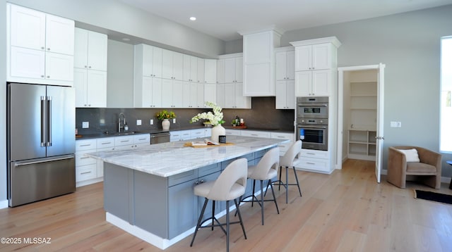 kitchen with white cabinetry, sink, a center island, stainless steel appliances, and a breakfast bar