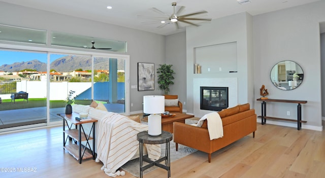 living room featuring a mountain view, ceiling fan, and light wood-type flooring