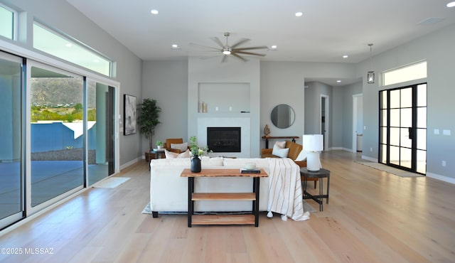 living room with ceiling fan, light wood-type flooring, and a wealth of natural light