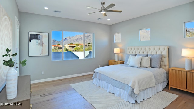 bedroom with ceiling fan, a mountain view, and light hardwood / wood-style floors