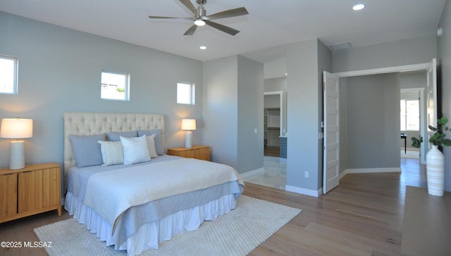 bedroom featuring multiple windows, hardwood / wood-style floors, and ceiling fan