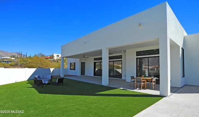 back of house with ceiling fan, a patio area, and a lawn