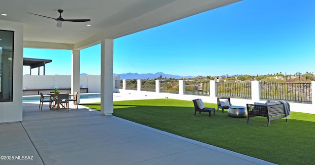 view of patio featuring a fenced in pool, a mountain view, and ceiling fan