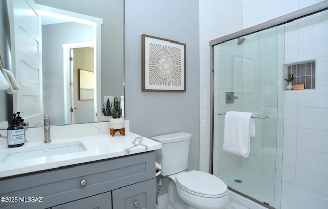 bathroom with vanity, toilet, and a shower with shower door