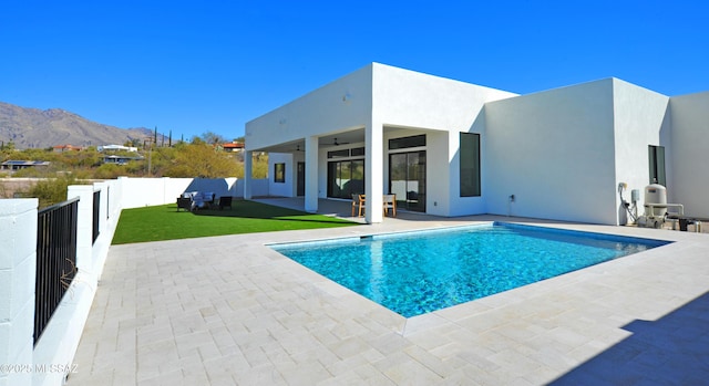 view of pool with a mountain view, ceiling fan, a patio area, and a yard