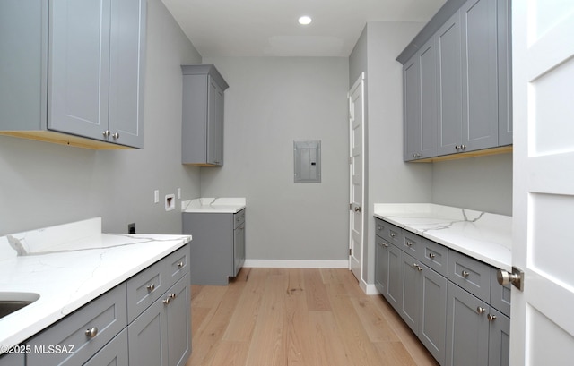 laundry area featuring cabinets, electric panel, washer hookup, light wood-type flooring, and hookup for an electric dryer