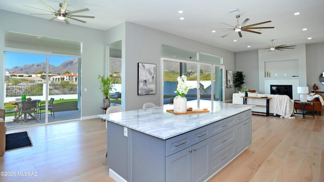 kitchen with a mountain view, plenty of natural light, light stone counters, and light hardwood / wood-style floors