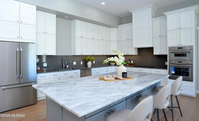 kitchen featuring a center island, stainless steel appliances, white cabinetry, and a breakfast bar area