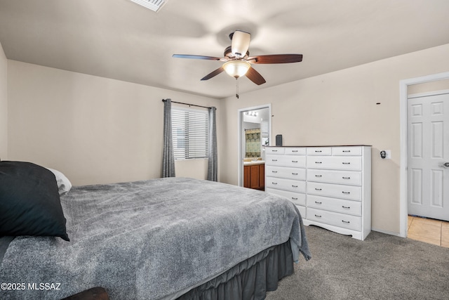 carpeted bedroom with ensuite bath and ceiling fan