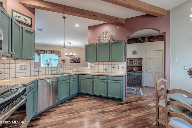 kitchen featuring appliances with stainless steel finishes, hanging light fixtures, light countertops, green cabinets, and a sink