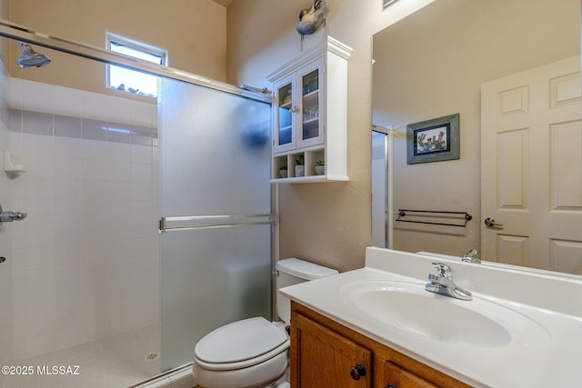 bathroom featuring toilet, tiled shower, and vanity