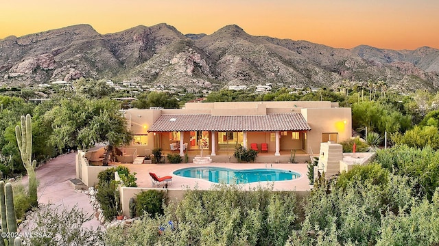 pool at dusk featuring a patio and a mountain view