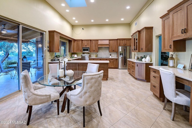 kitchen with light tile patterned floors, a breakfast bar, a skylight, stainless steel appliances, and a high ceiling