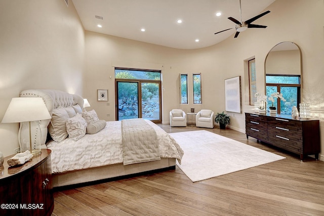 bedroom with access to exterior, a high ceiling, and light wood-type flooring