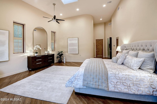 bedroom featuring ceiling fan, dark wood-type flooring, high vaulted ceiling, and a skylight