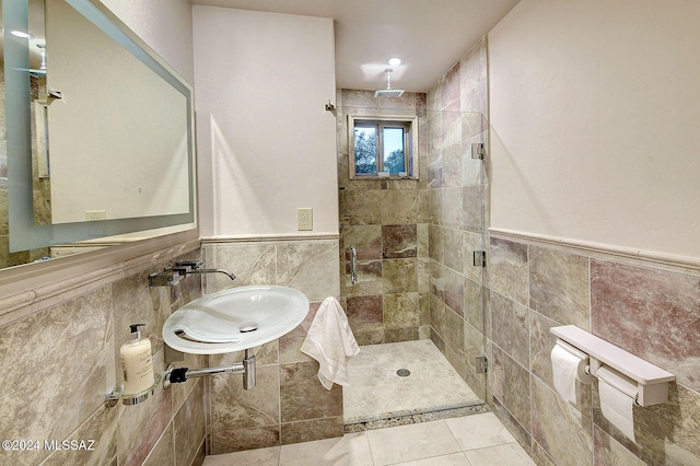 bathroom with tile patterned flooring, a shower with door, sink, and tile walls