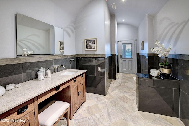 bathroom featuring vanity, vaulted ceiling, and tile walls