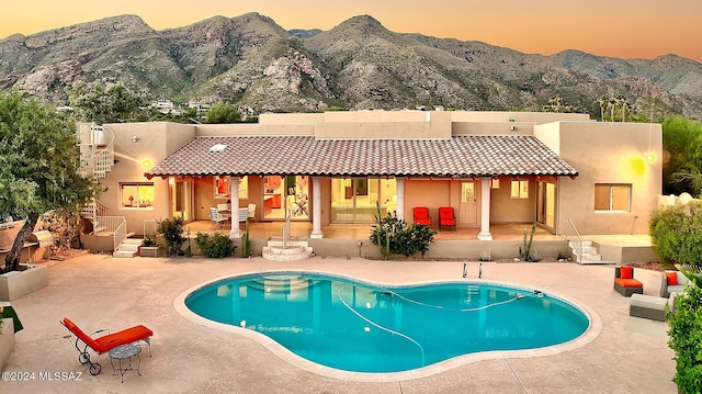 pool at dusk with a mountain view and a patio