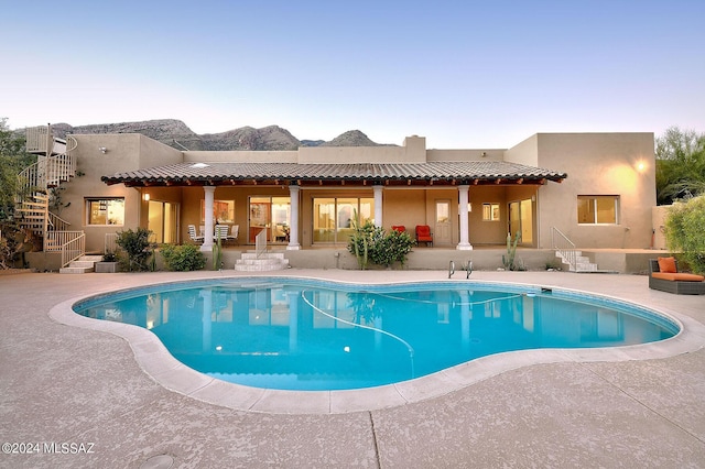 pool at dusk with a patio and a mountain view