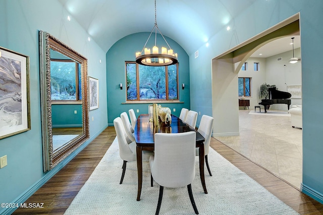 dining area with an inviting chandelier, hardwood / wood-style floors, and lofted ceiling