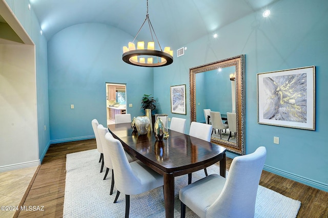 dining room featuring hardwood / wood-style flooring, high vaulted ceiling, and a chandelier