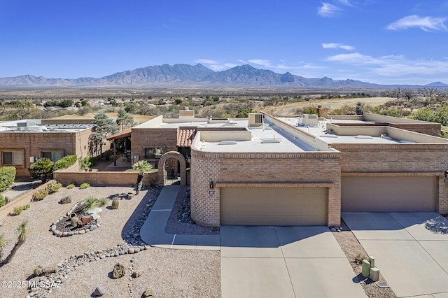 view of front facade with driveway, a mountain view, and brick siding