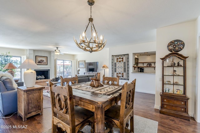 dining area featuring dark wood-style floors, a wealth of natural light, a fireplace, and baseboards