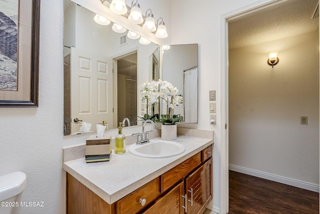 bathroom with visible vents, toilet, vanity, wood finished floors, and baseboards