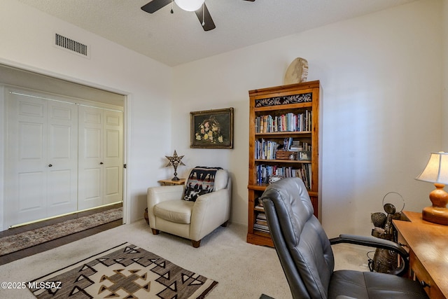 office space with ceiling fan, visible vents, a textured ceiling, and light colored carpet