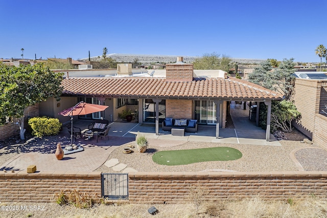 back of property featuring an outdoor living space, a patio area, a tile roof, and a chimney