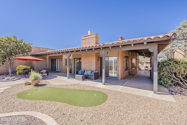 rear view of house with outdoor lounge area, a chimney, a patio area, and a tile roof