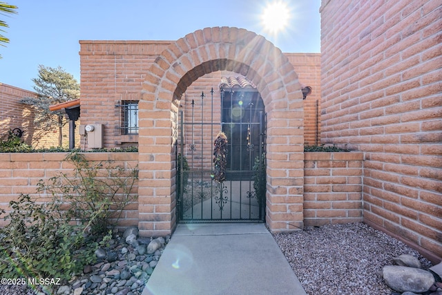 property entrance featuring brick siding, fence, and a gate