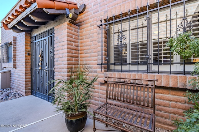 view of exterior entry with brick siding and a gate