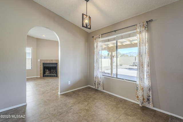 unfurnished dining area featuring a textured ceiling, light tile patterned floors, and a tile fireplace