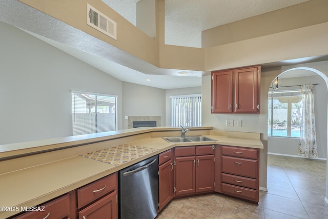 kitchen with sink, stainless steel dishwasher, a tile fireplace, and light tile patterned flooring