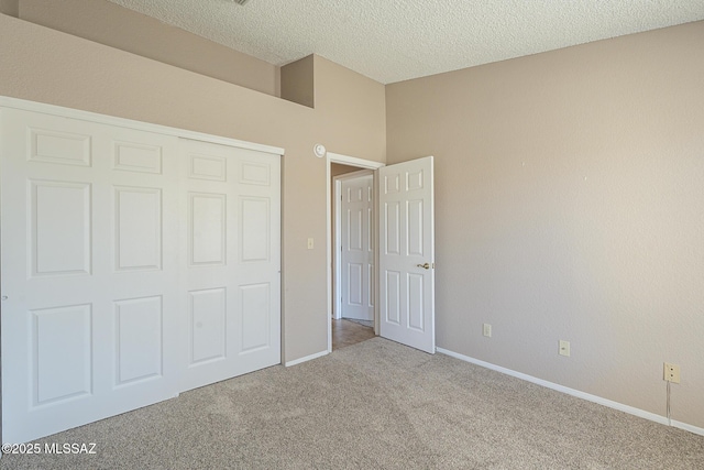 unfurnished bedroom with a textured ceiling, a closet, and light carpet