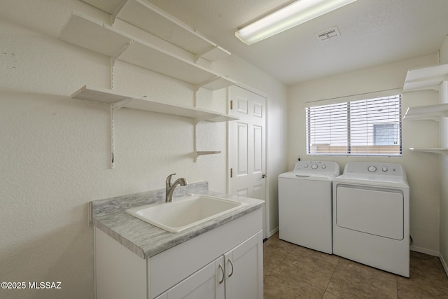 clothes washing area with cabinets, sink, light tile patterned floors, and washing machine and clothes dryer