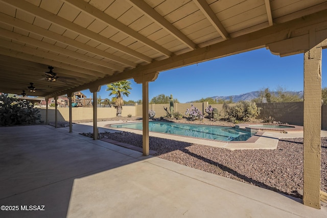 view of swimming pool with an in ground hot tub, a mountain view, ceiling fan, and a patio