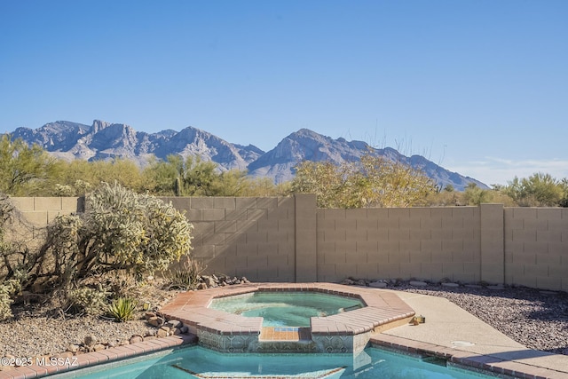 view of swimming pool with a mountain view and an in ground hot tub